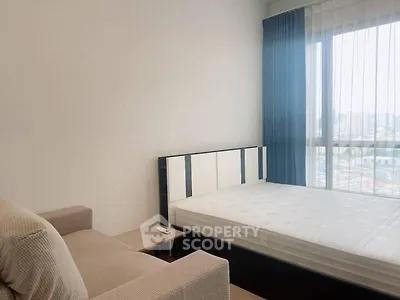 Modern bedroom with large window and cozy sofa, perfect for urban living.