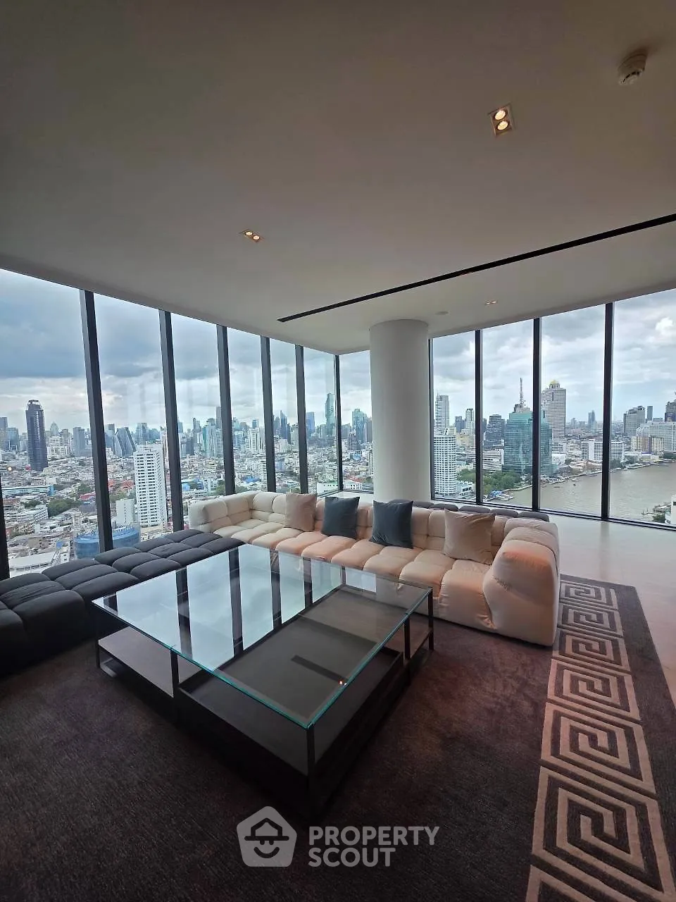 Luxurious corner unit living room with panoramic city skyline views and modern furnishings.