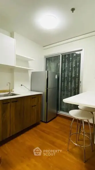 Modern kitchen with sleek cabinets and stainless steel fridge in cozy apartment.