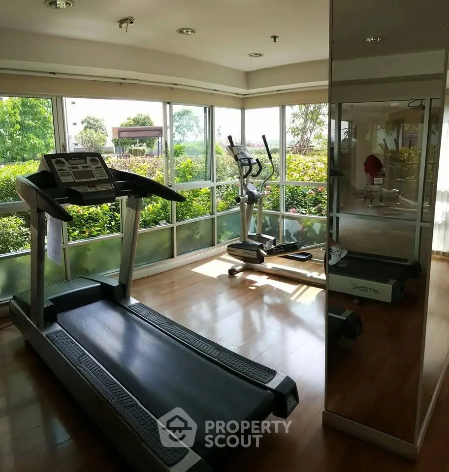 Bright home gym with treadmill and exercise bike overlooking lush garden view.