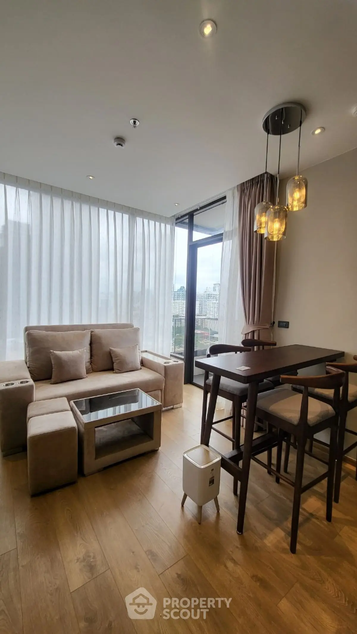 Modern living room with elegant furniture and large windows offering city views.