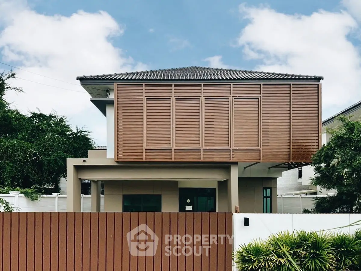 Modern two-story house with wooden facade and lush greenery