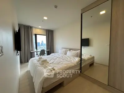 Modern bedroom with city view, featuring a cozy bed, mirrored wardrobe, and wall-mounted TV.