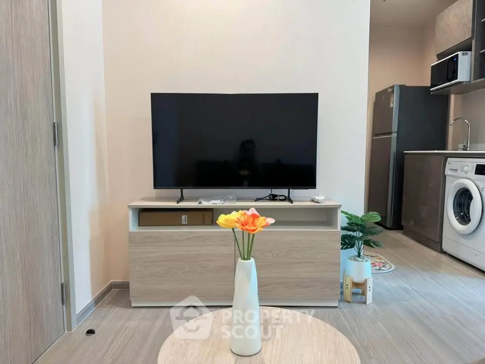 Modern living room with sleek TV, stylish furniture, and contemporary kitchen appliances.