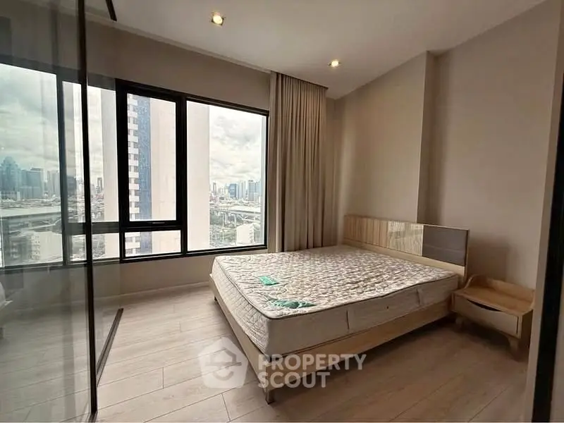Modern bedroom with large windows offering stunning city views and natural light.