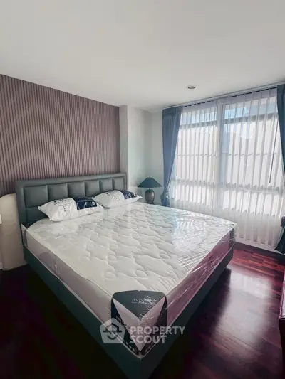 Spacious bedroom with modern decor and large windows for natural light.