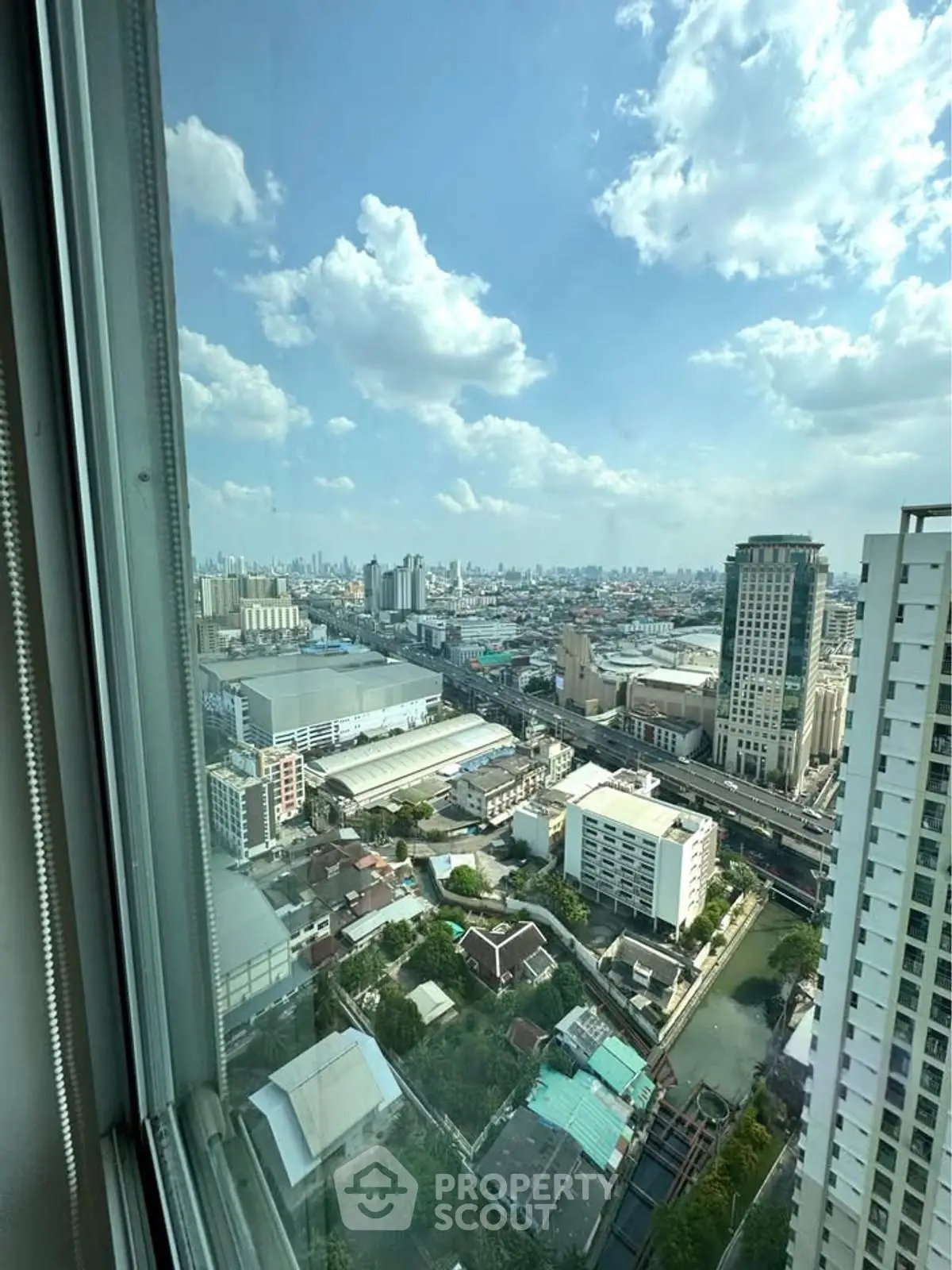 Stunning cityscape view from high-rise window showcasing urban skyline and blue sky.