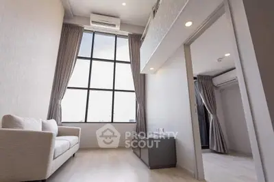 Spacious modern living room with high ceiling and large window, featuring elegant curtains and a cozy sofa.