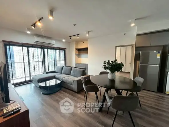 Spacious modern living room with large windows and stylish furniture in a high-rise apartment.