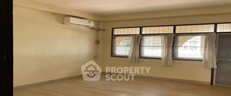 Spacious unfurnished room with large windows and air conditioning, ideal for customization.