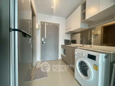 Modern kitchen with sleek appliances and washing machine in compact layout