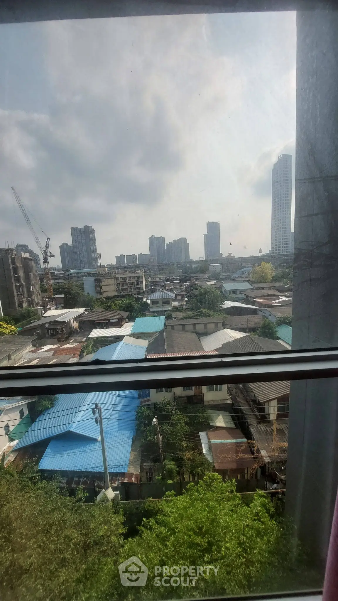 Stunning cityscape view from a high-rise window showcasing urban skyline and residential rooftops.