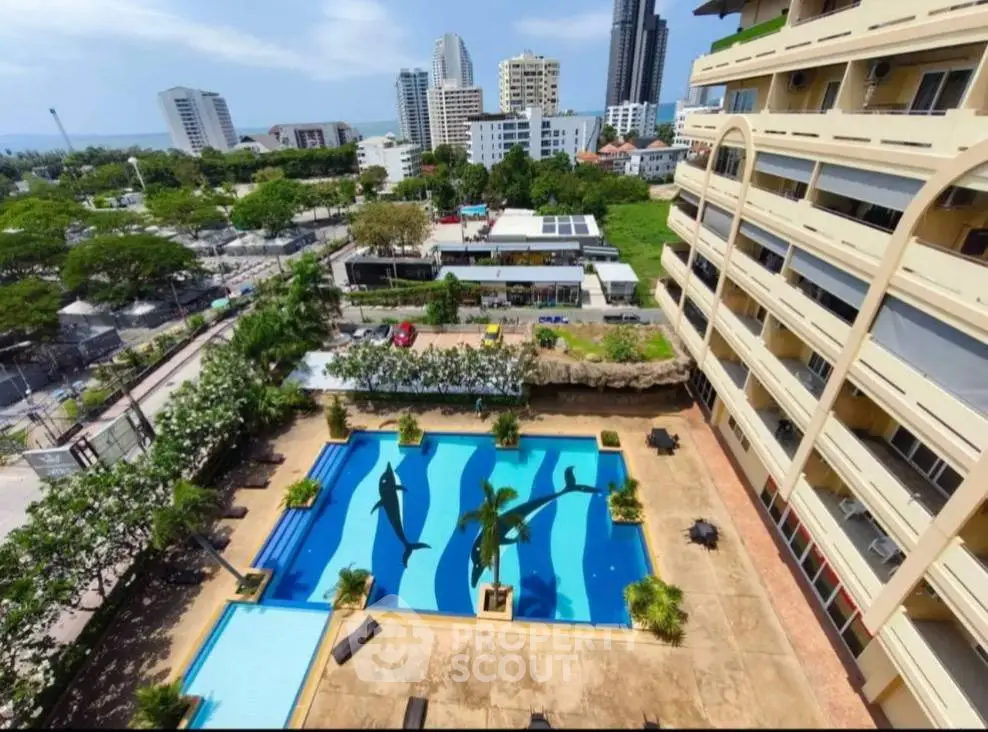 Stunning aerial view of a luxurious apartment complex with a beautiful pool and cityscape backdrop.