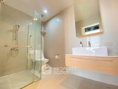 Modern bathroom with glass shower and sleek vanity in a contemporary home.