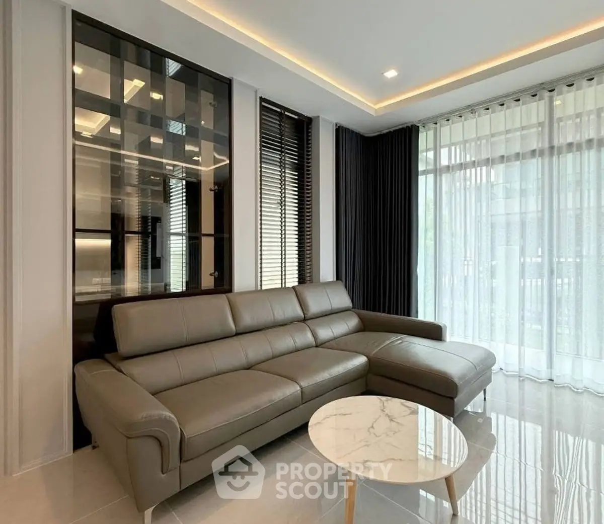 Modern living room with sleek leather sofa and marble coffee table, featuring floor-to-ceiling windows and elegant decor.