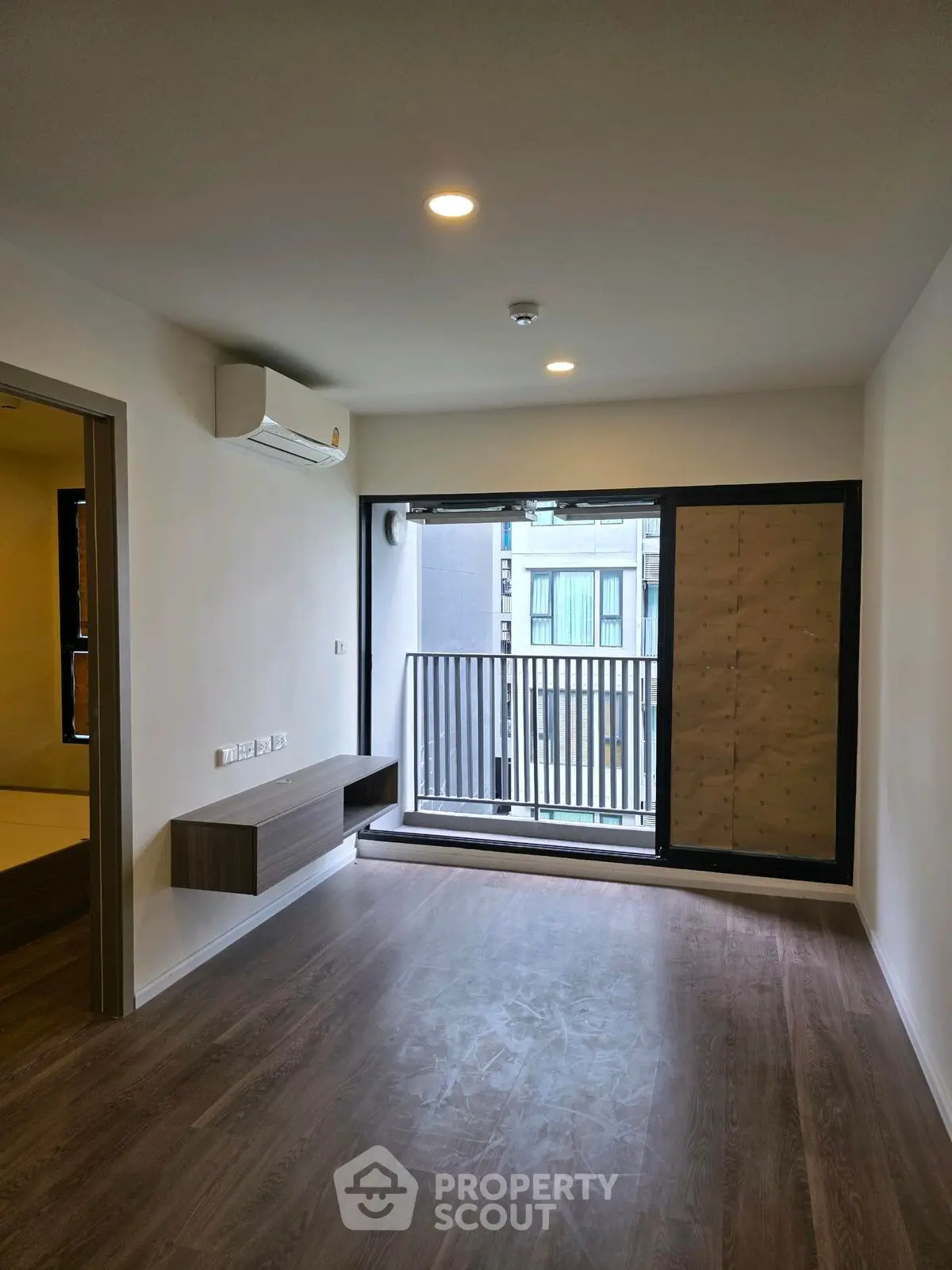 Modern living room with balcony access and sleek wooden flooring.