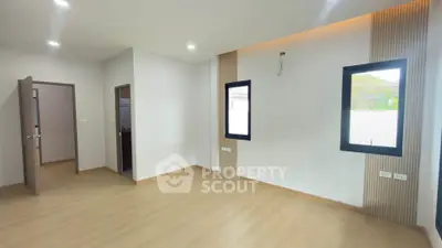 Spacious modern room with wooden flooring and large windows, perfect for customization.
