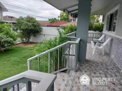 Charming garden view from spacious balcony with tiled flooring and cozy seating area.