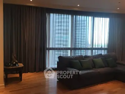 Spacious living room with large windows and modern sofa in high-rise apartment.