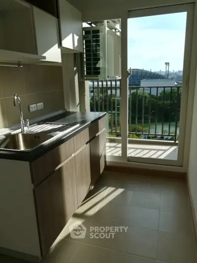 Modern kitchen with sleek cabinetry and balcony view, featuring natural light and compact design.