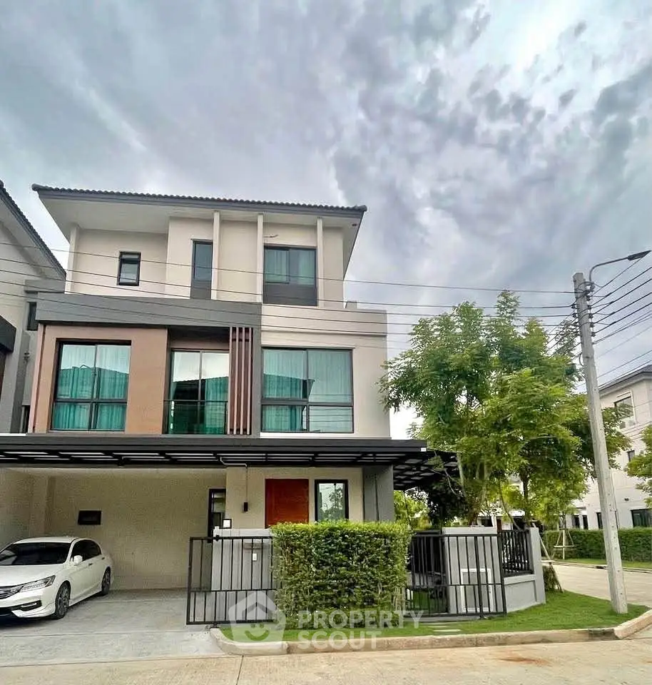 Modern three-story house with carport and lush greenery in a serene neighborhood.