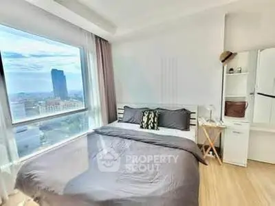 Bright bedroom with large window offering stunning city view, modern decor, and ample natural light.