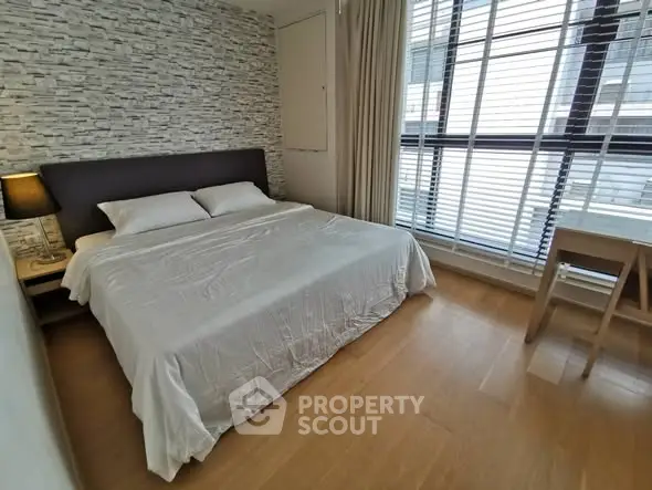 Modern bedroom with large window and stylish decor in a contemporary apartment.