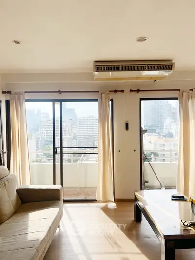 Bright living room with large windows and city view, featuring cozy sofa and modern decor.