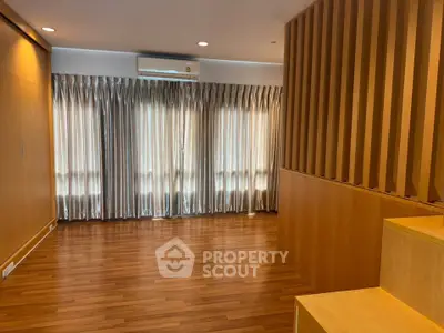Spacious modern living room with wooden flooring and elegant curtains