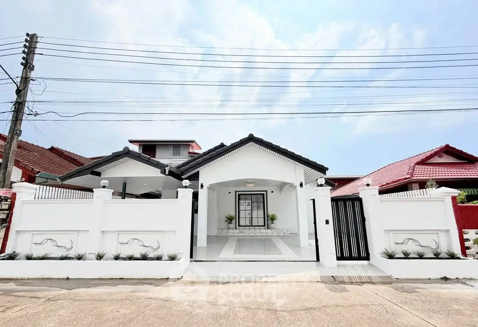 Charming single-story white house with modern facade and gated entrance in a serene neighborhood.