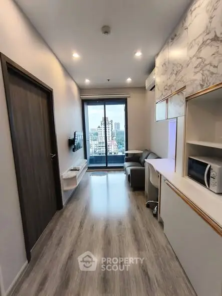 Modern living room with city view, sleek flooring, and built-in storage in a high-rise apartment.