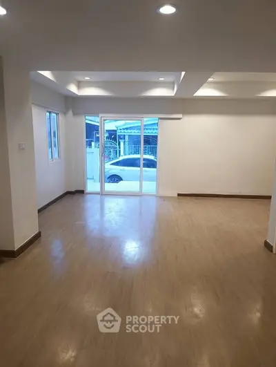 Spacious open-plan living room with large windows and wooden flooring, perfect for modern living.