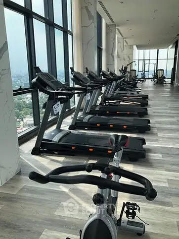 Luxurious high-rise gym with panoramic city views and modern fitness equipment.
