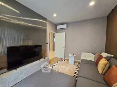 Modern living room with sleek design, featuring a large TV, comfortable sofa, and stylish decor.