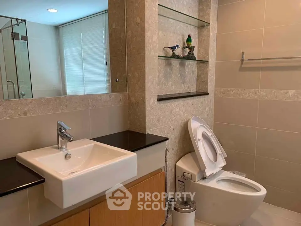 Modern bathroom with sleek fixtures and elegant design, featuring a glass shower and stylish sink.
