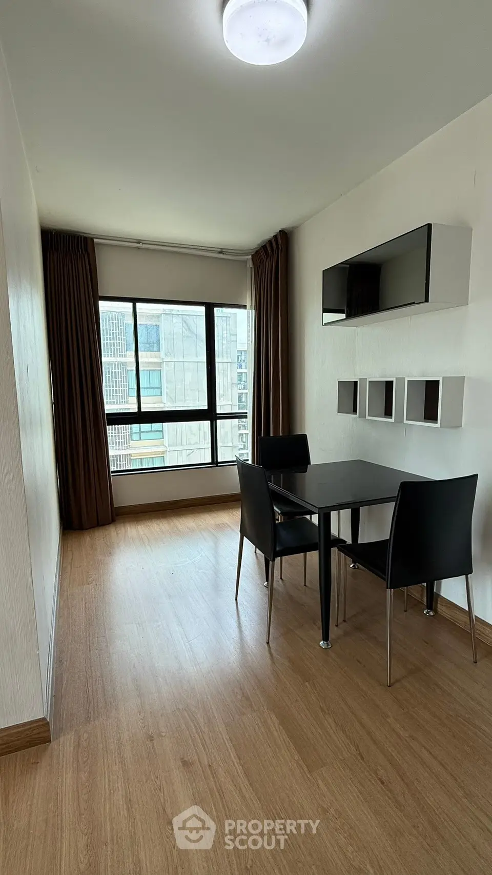 Modern dining area with sleek table and chairs, large window, and stylish wall shelves in a bright apartment.