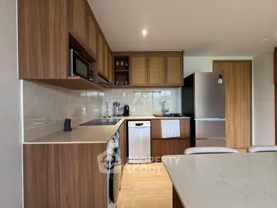 Modern kitchen with wooden cabinets, stainless steel appliances, and washing machine in a sleek open layout.