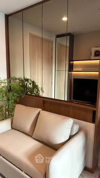 Modern living room with sleek design, featuring a comfortable sofa and mirrored wall for spacious feel.