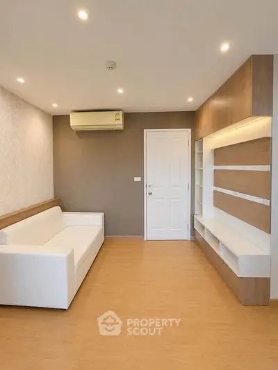 Modern living room with sleek design, featuring a white sofa, built-in shelves, and wooden flooring.