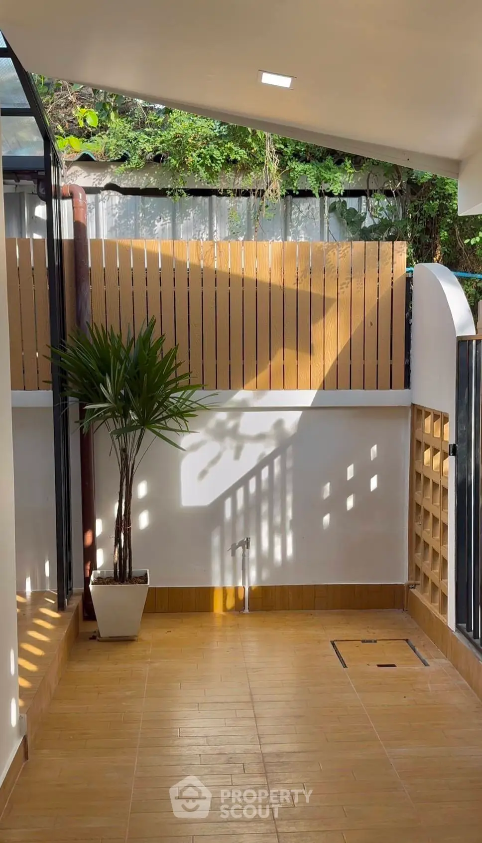 Charming outdoor patio with modern wooden fencing and lush greenery, perfect for relaxation and entertaining.