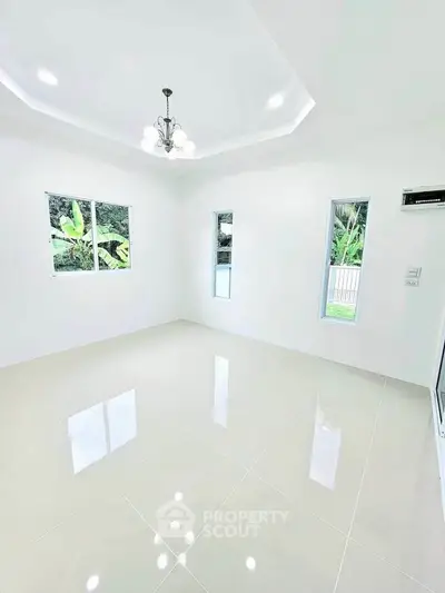 Bright and spacious living room with glossy tile flooring and modern chandelier.