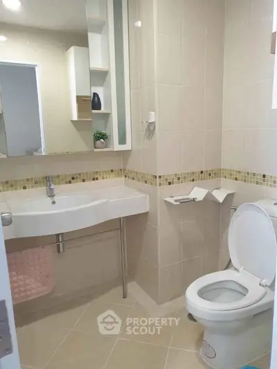 Modern bathroom with sleek fixtures and neutral tiles, featuring a spacious sink and toilet.