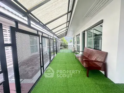 Spacious balcony with artificial grass and wooden bench, offering a serene outdoor retreat.