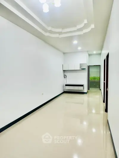 Spacious and modern empty living room with sleek ceiling design and polished floors.