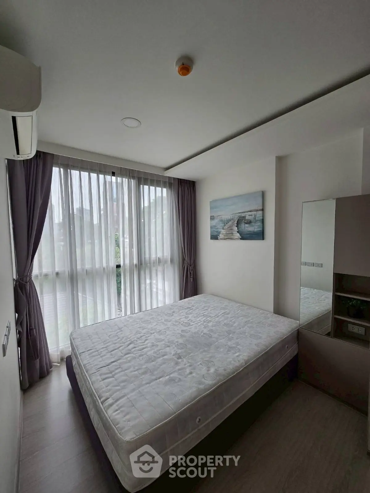 Spacious bedroom with large window and modern decor in a stylish apartment.