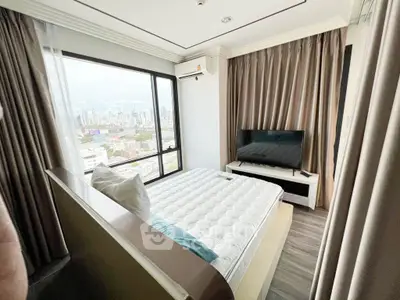 Modern bedroom with city view, featuring a large window, TV, and stylish decor.