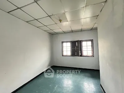Spacious empty room with tiled ceiling and large windows, perfect for customization.