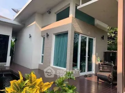Modern house exterior with large windows and lush garden, perfect for serene living.