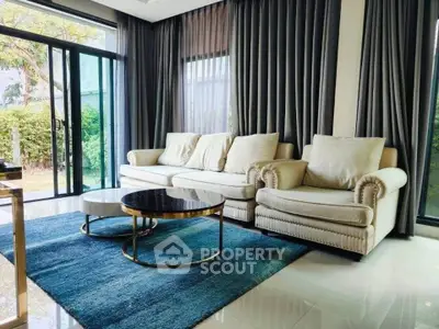 Luxurious living room with elegant sofa and modern decor, featuring large windows and lush garden view.