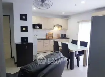 Modern open-layout kitchen and living area with sleek furniture and ample lighting.